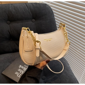 Détail du sac beige à texture tissée avec chaîne dorée et étiquette en cuir poli
