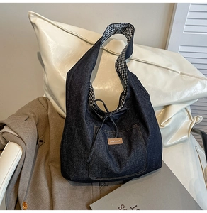 Détail d'un sac cabas en jean bleu avec étiquette en cuir et doublure à carreaux chic