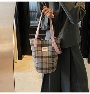 Detail of vintage plaid tote bag featuring pink handles and woven tweed fabric texture