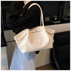 Detail of white lychee leather tote bag featuring gold buckle and side adjustable straps