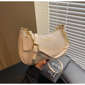 Détail du sac demi-lune tressé beige avec chaîne dorée et bandoulière en cuir souple