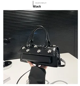 Détails des clous en métal argenté sur un sac en cuir verni noir avec finition polie