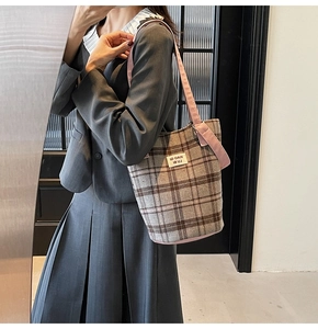 Detail of plaid tote bag with pink straps worn by a model in a retro blazer outfit