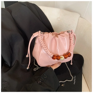 Detail of pink quilted bucket bag with amber beads and silver chain on black blazer