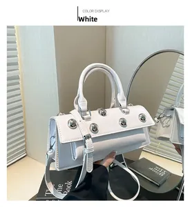 Détail d'un sac à main blanc en PU brillant avec rivets argentés et bandoulière