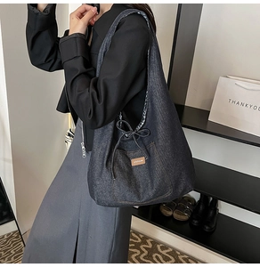 Détail du grand sac cabas en jean avec cordon de serrage à nœud et étiquette de marque en cuir