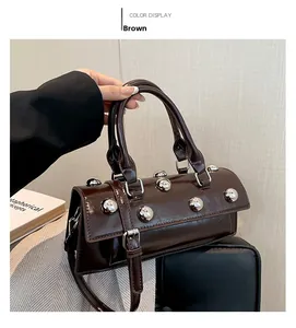 Détail d'un sac à main marron en cuir verni avec des rivets argentés et poignée supérieure