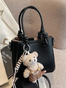 Chic black litchi grain leather bucket bag with a knotted handle and cute bear charm