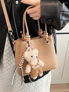 Chic light brown lychee grain bucket bag with teddy bear charm and adjustable shoulder strap