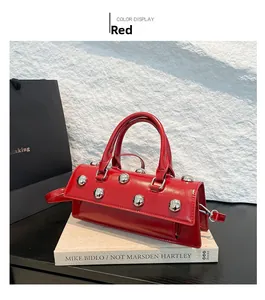 Détail d'un sac baguette en cuir verni rouge avec rivets argentés et poignée top