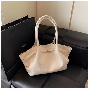 Detailed macro view of the textured lychee leather grain on the creamy white tote bag