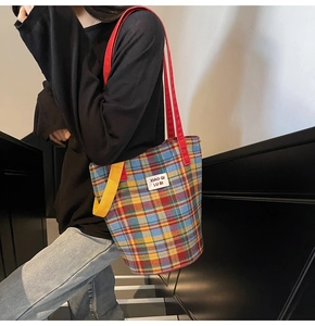 Close-up of colorful checkered tote bag with woven texture and a brand label detail