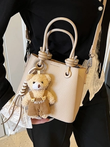 Chic beige lychee grain bucket bag with a cute bear charm and adjustable strap