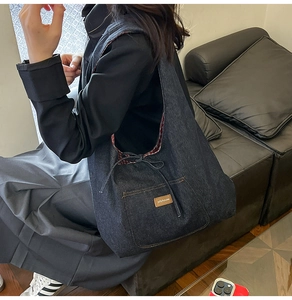 Vue détaillée du sac en jean avec doublure à carreaux rouges et étiquette en cuir