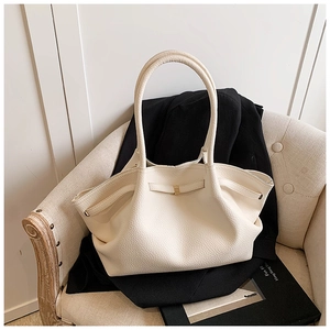 Close-up of litchi texture leather tote bag with elegant gold buckle and cream finish