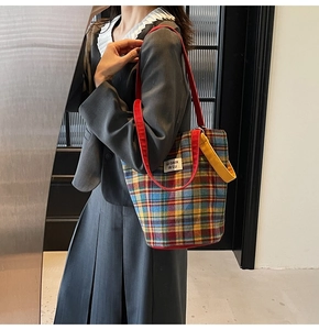 Detail of colorful plaid tote bag with red shoulder straps and yellow top handle
