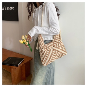 Detail of hand-woven crochet hobo bag with geometric patterns and fringe tassel accents