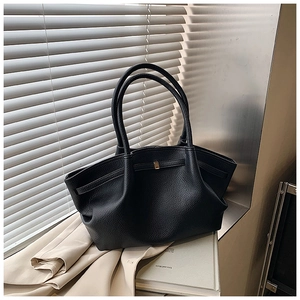 Detail of black pebbled leather tote bag with gold buckle on office desk setting