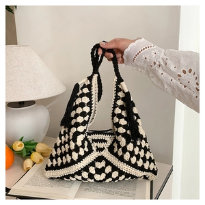 Detail of black and white crochet knit tote bag with long fringe tassels on book