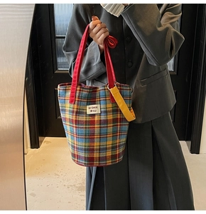 Close-up of retro plaid canvas tote featuring red webbing straps and woven fabric detail