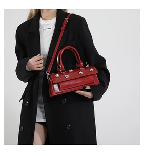 Détail du sac en cuir brillant rouge avec des clous argentés et doubles poignées élégantes