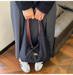 Détail du sac cabas en jean montrant la doublure à carreaux rouges et le cordon
