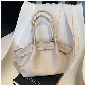 Close-up of beige pebble leather tote bag showing unique pleated design and metal buckle