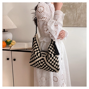 Detail of hand-woven crochet shoulder bag with black and white heart motifs and tassels