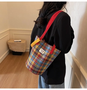 Detail of multi-color plaid canvas tote bag worn over the shoulder by a model