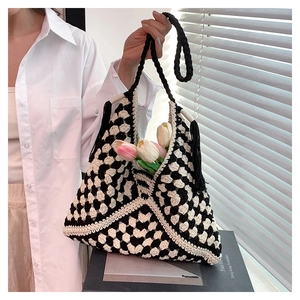 Detail of hand-woven checkerboard crochet tote bag featuring black fringe and long straps