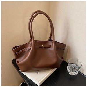 Detail of caramel brown pebble leather tote bag with sturdy handles and gold metal buckle