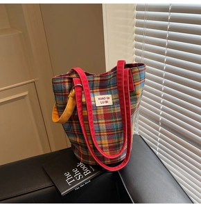 Detail of tartan tote bag featuring plaid canvas material with colorful shoulder straps