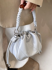 Light blue quilted bucket bag with woven handle and amber beads for chic commute