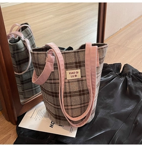 Detail of vintage plaid tote bag with pink contrast shoulder strap and branded label