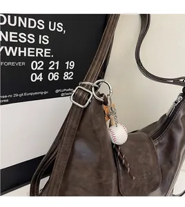 Detail of dark brown vintage hobo bag with baseball charm and silver metal hardware strap