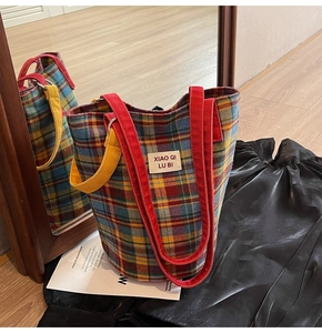 Close-up of vintage plaid canvas tote bag with colorful check pattern and red woven strap