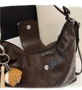 Detail of dark brown wax leather tote with silver hardware and baseball keychain accessory