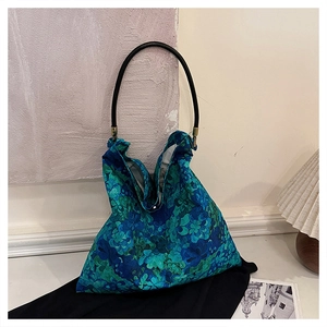Detail of floral fabric tote bag with black round handle and brass metal hardware