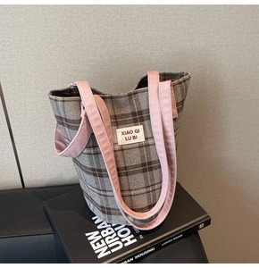 Macro detail of plaid tote bag featuring pink contrast handles and fabric texture