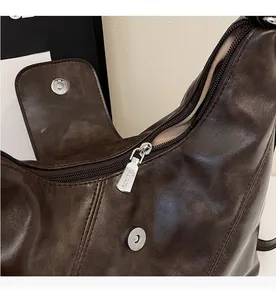 Close-up of vintage brown leather tote showing silver zipper and stitching detail