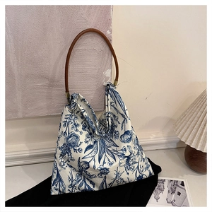 Detailed close-up of a floral canvas tote bag with wooden handle and Toile de Jouy print