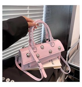 Détail du sac baguette rose avec des rivets argentés et une poignée de transport chic