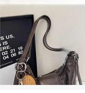 Detail of dark brown leather tote bag with silver hardware and heart charm decoration