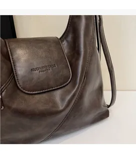 Close-up of vintage brown PU leather texture and debossed logo on fashion tote bag