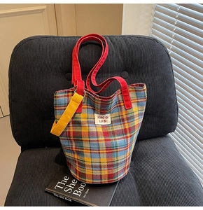 Macro detail of a colorful checkered canvas tote bag with red handles on a velvet chair
