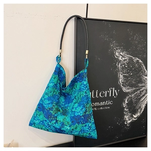 Detailed close-up of blue-green floral embroidery on a canvas tote bag hanging on frame