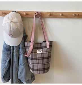 Detail of the gray plaid textured fabric and pink cotton strap of the tote bag