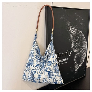 Close-up of floral embroidery tote bag with brown leather handles and metal rings