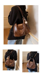 Close-up of brown soft leather tote bag with logo magnetic flap and baseball charm detail
