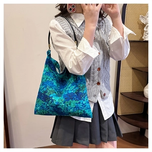 Detailed close-up of blue floral print fabric and slim black strap on this tote bag